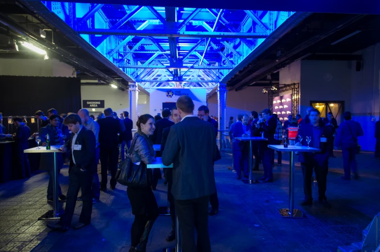 people mingling in a building with blue lights