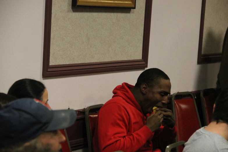 a man with red hoodie eating food in a restaurant