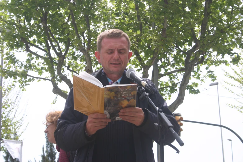 man reading a book in front of two trees