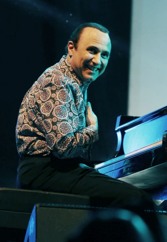 a smiling man sitting at the piano