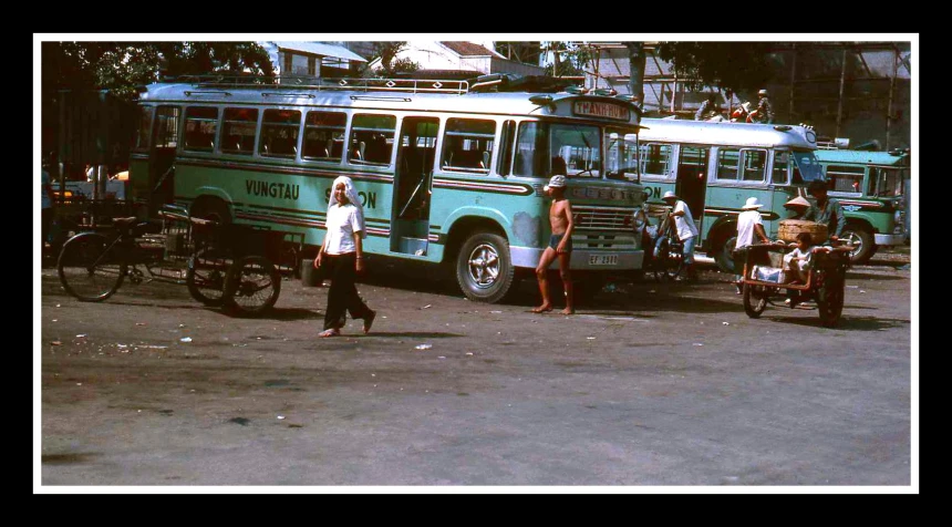 three buses are shown with many people in the background