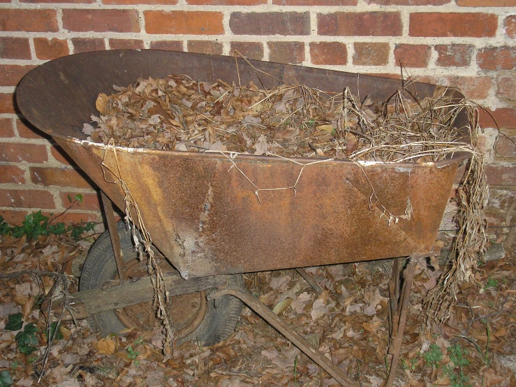 old rusty tub and wheel against a brick wall