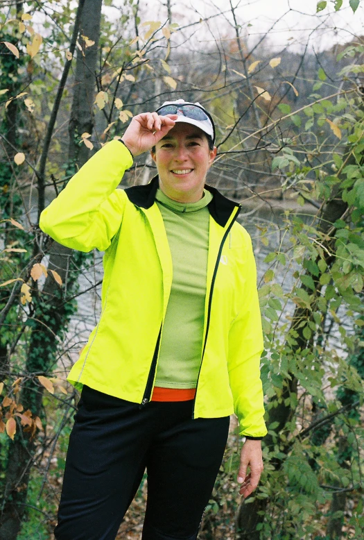 a woman smiles at the camera while wearing a bright jacket and cap