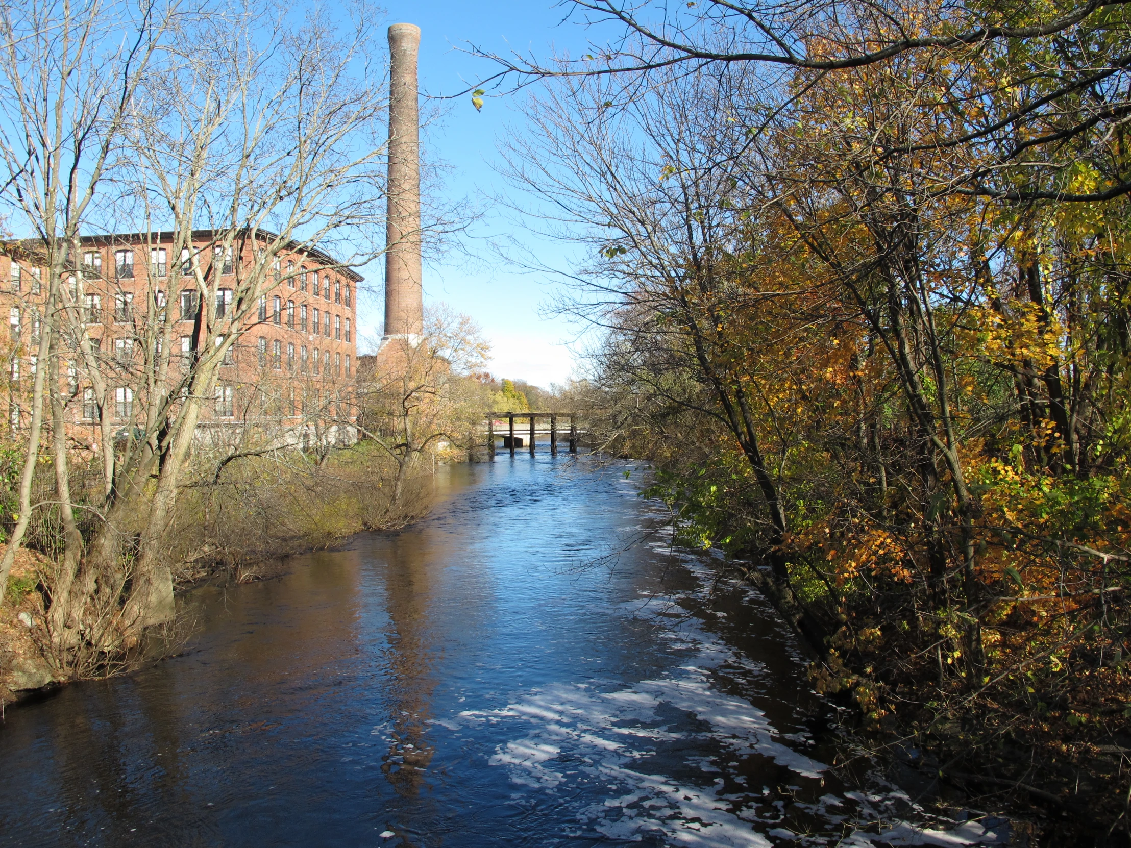 a river runs next to a power plant in autumn