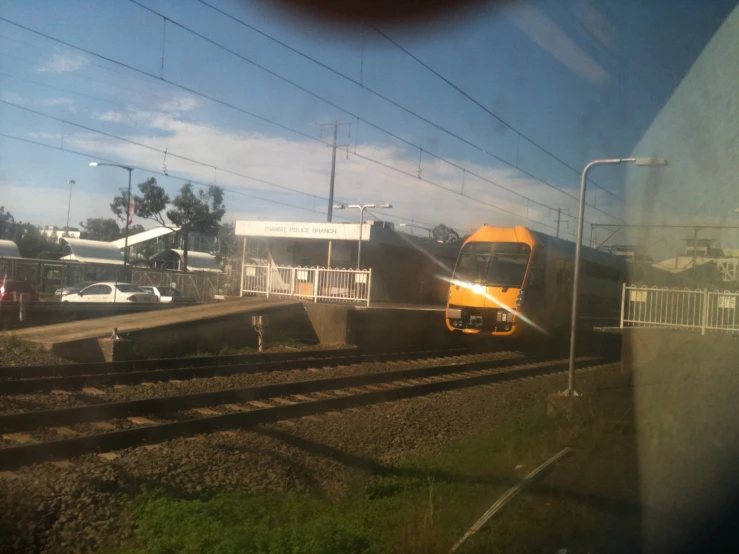 a yellow train moving down the tracks by buildings