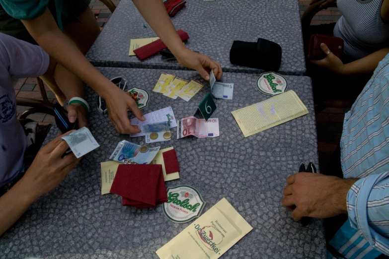 several people sit around a table, playing cards