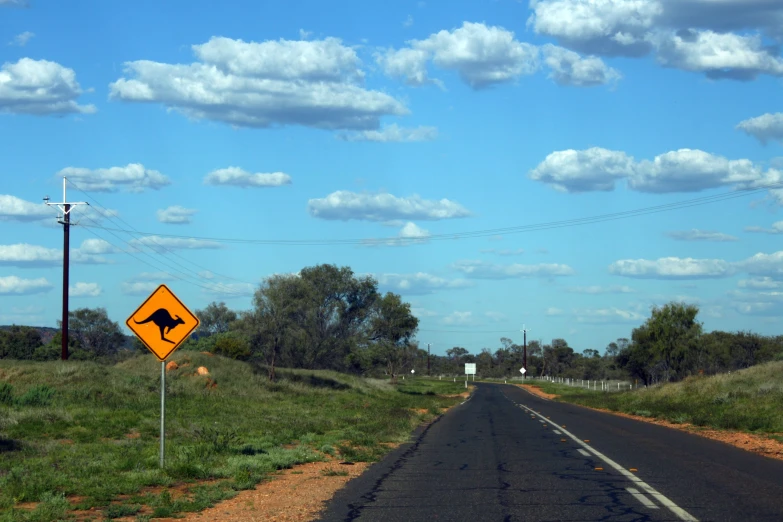 a yellow sign is sitting on the side of a road