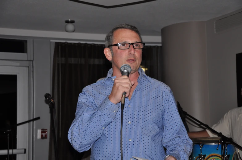 a man is singing into a microphone while standing at a table