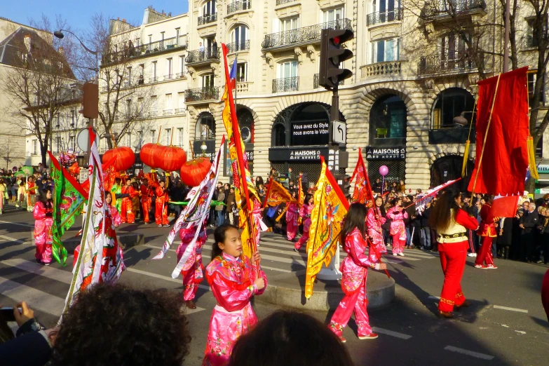 people in traditional attire marching down the street at a parade