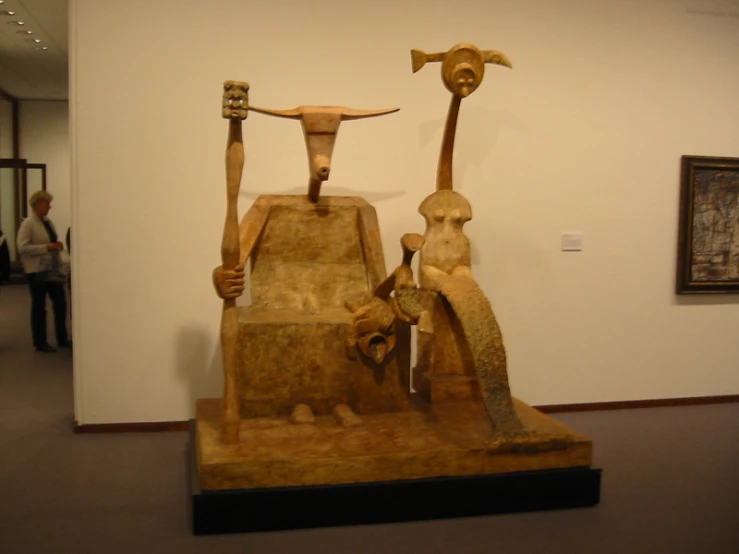 a wooden statue of two people holding spears