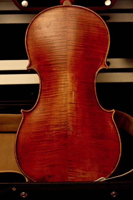 an old, well - worn cello sits against a wall