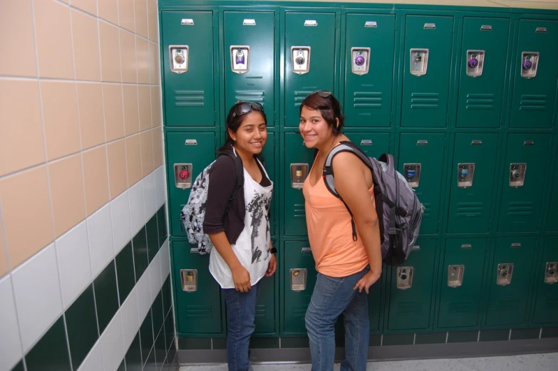 two female students posing in front of lockers at school