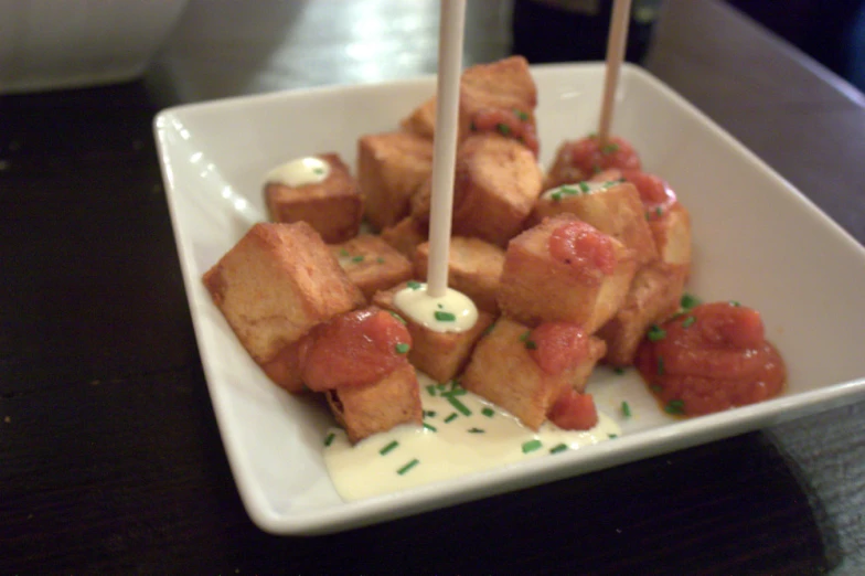 a white plate topped with tofu bites and sauce