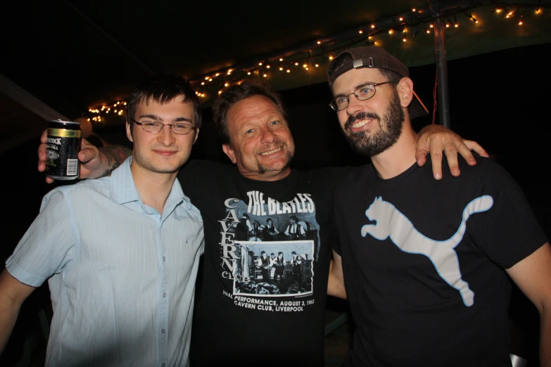 three men pose for a po under the lights