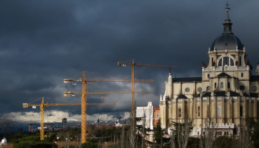 several cranes are standing in front of a very tall building