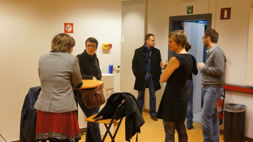 a group of people are standing around an office talking