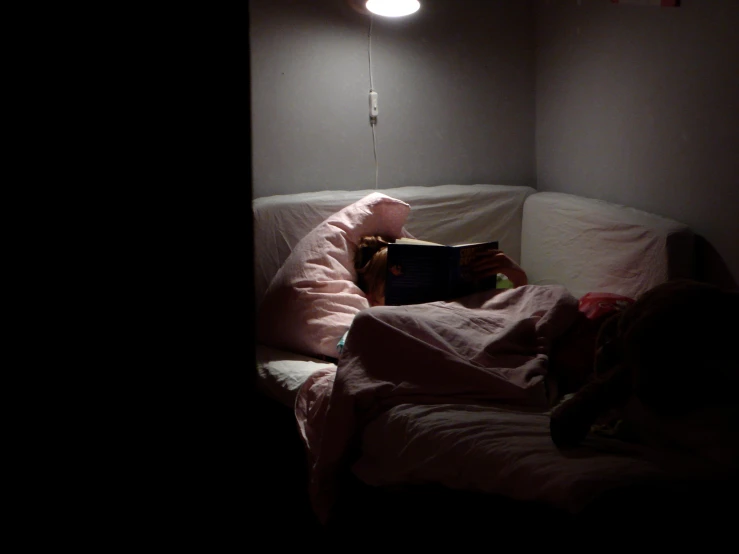 a person sitting on top of a bed next to a lamp