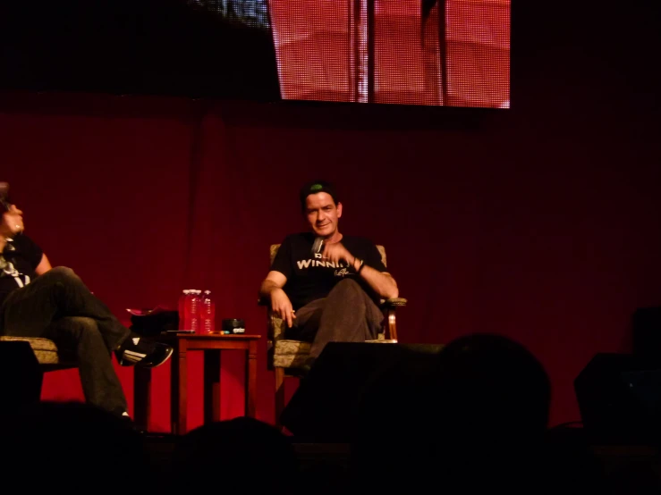 a pair of men sitting next to each other on stage