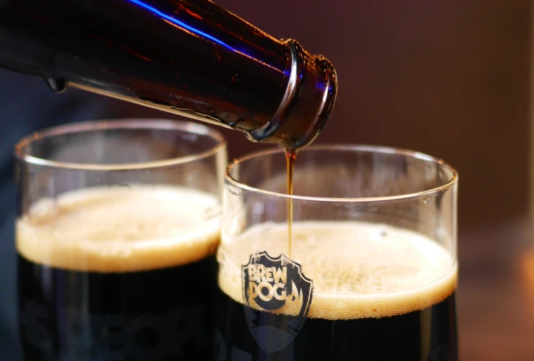 a man pouring beer into two glasses on the counter