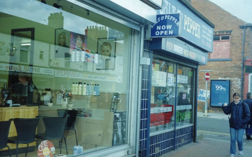 a person walking past a shop with a reflection in it's glass door