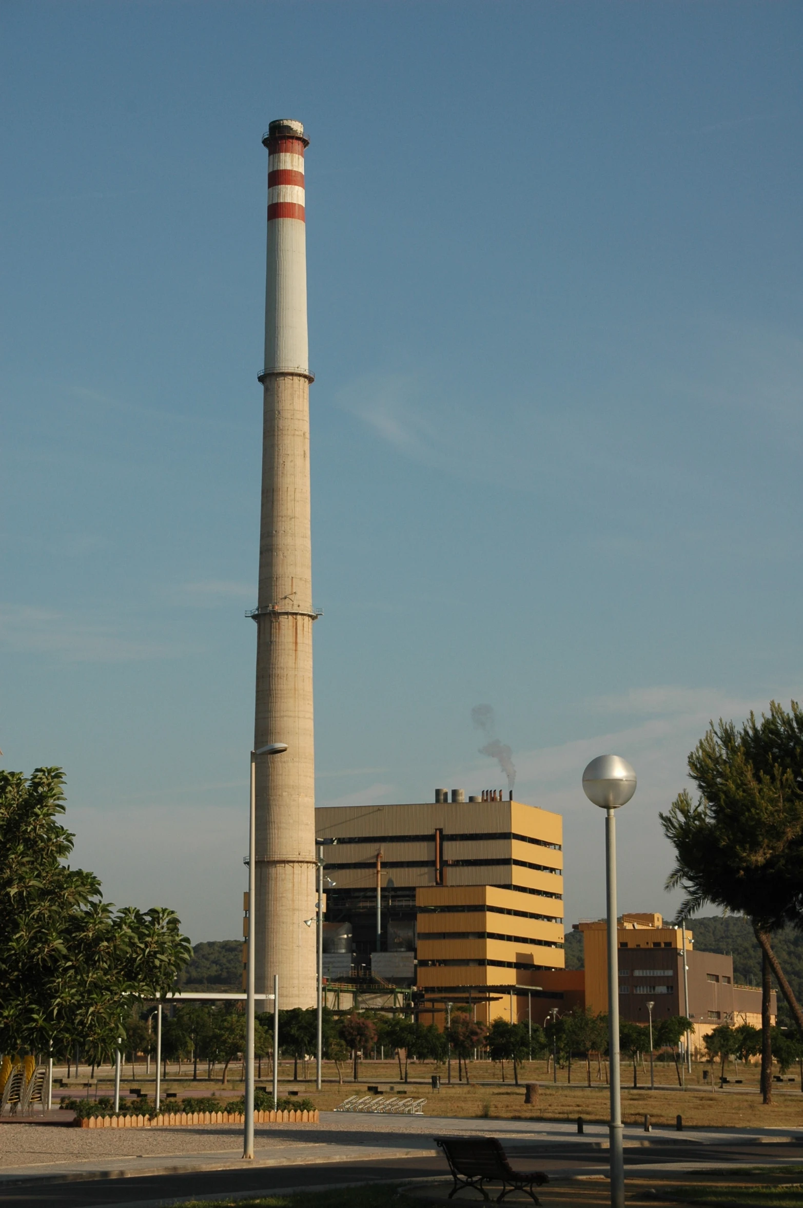 a factory with two large chimneys and a light pole