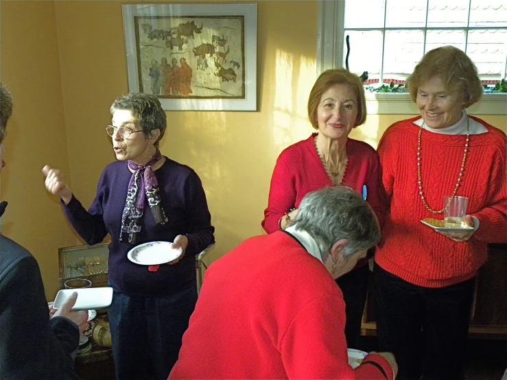 four elderly women with one holding a plate in front of them