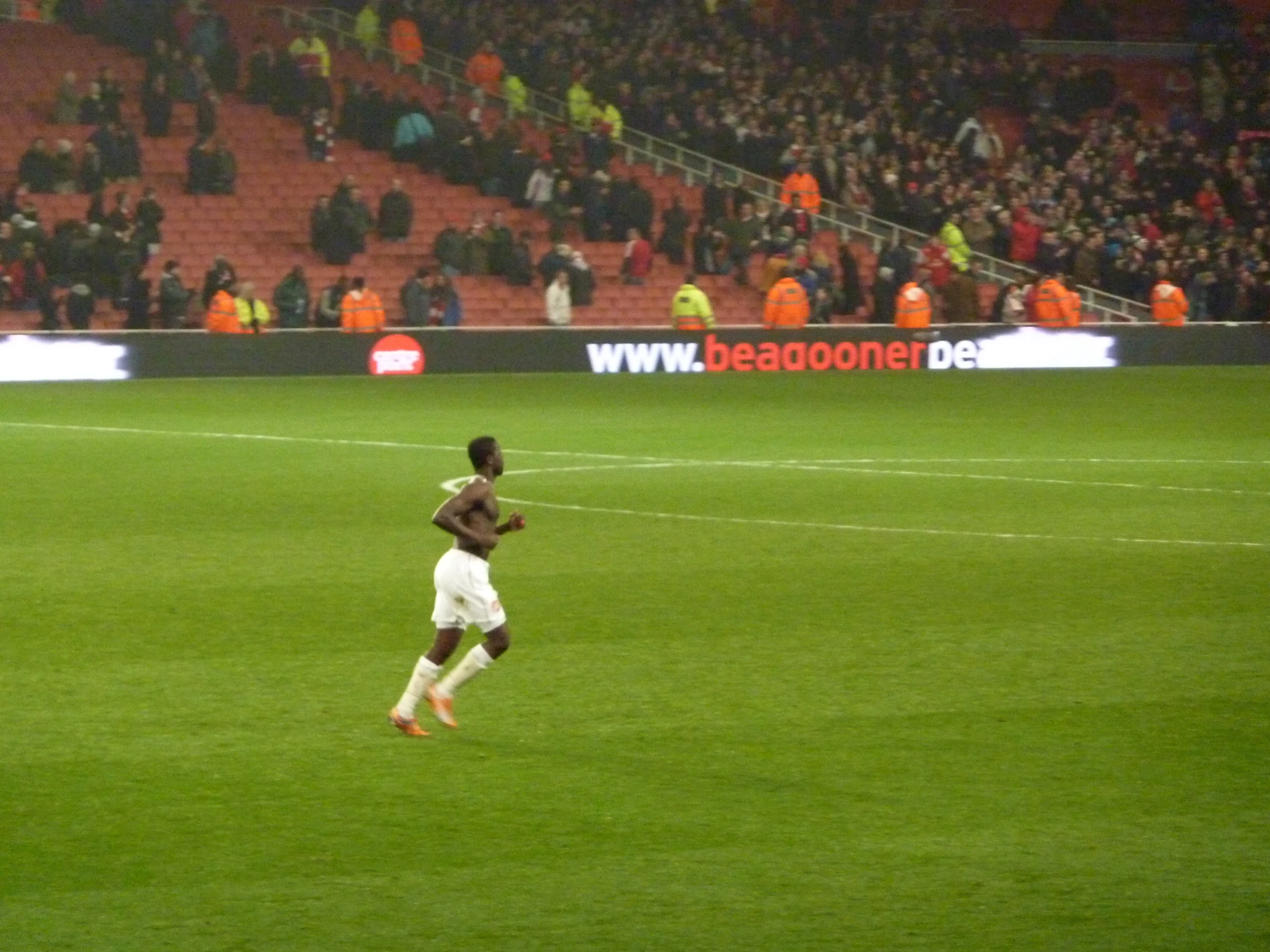 a woman running across a field towards a soccer ball