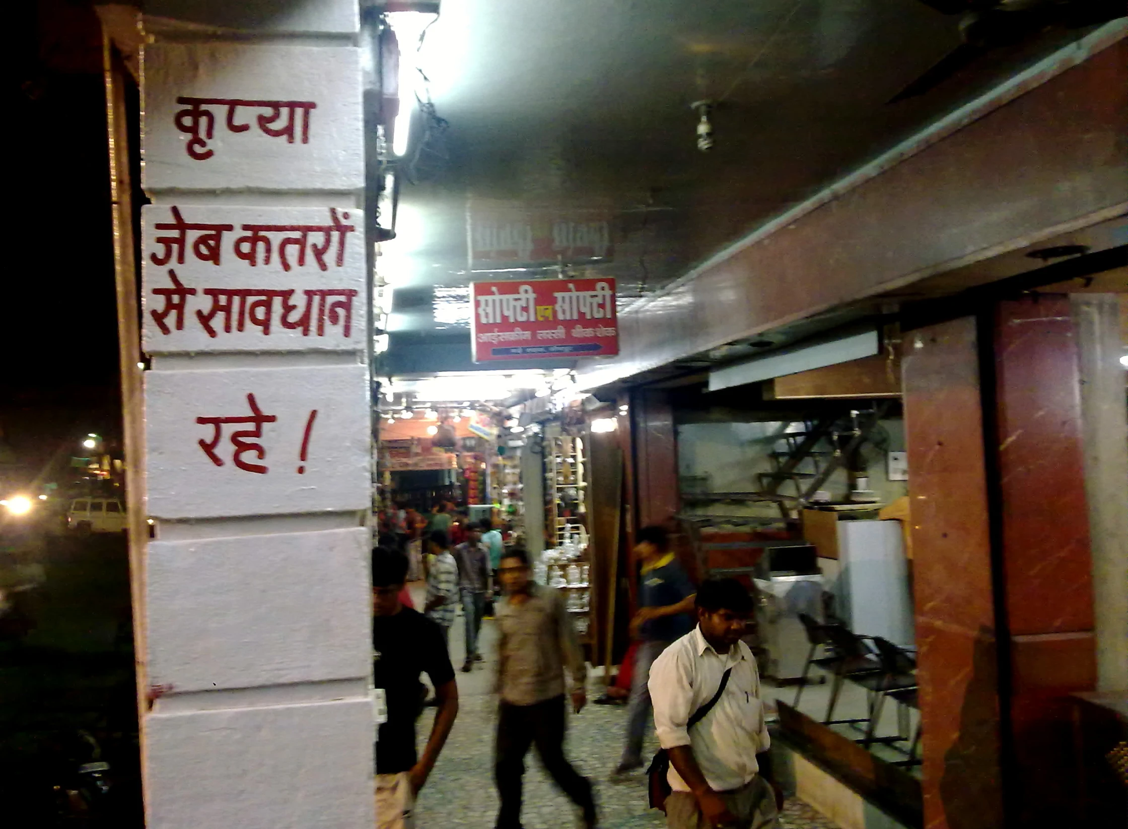 some people are walking inside a market on the sidewalk