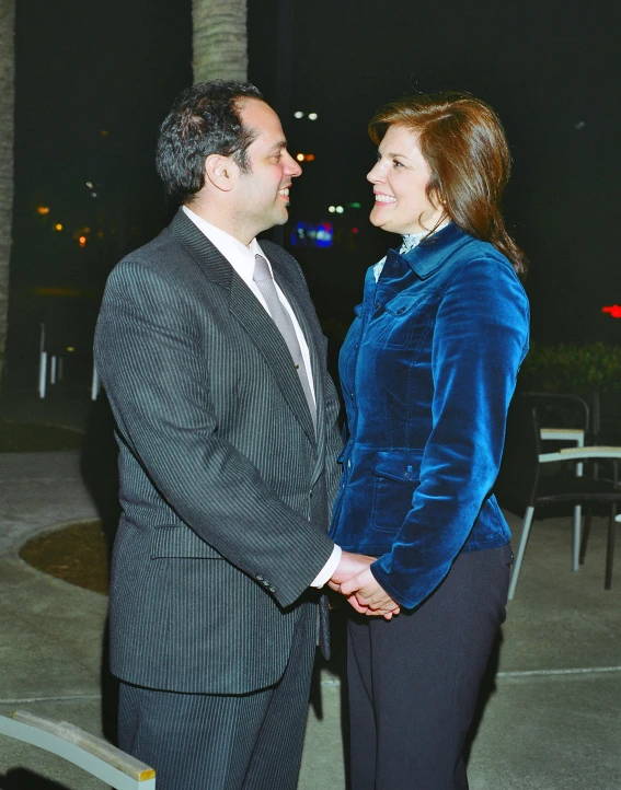 a woman and man standing close together near a tree