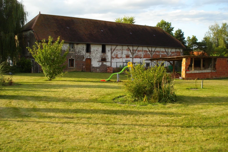 a old farm house with a green lawn and a large shed
