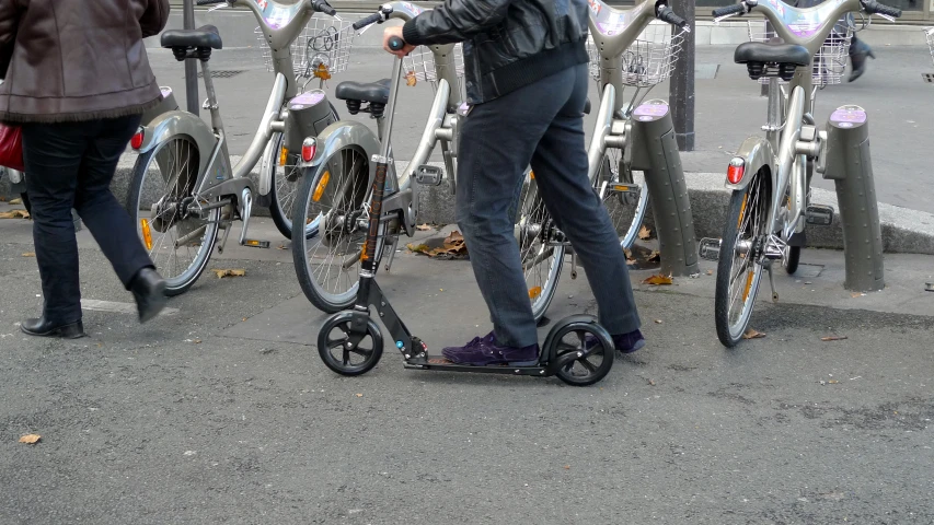 a man stands on the sidewalk with several bikes behind him