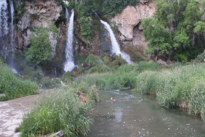 this is a man standing in the river watching some water fall