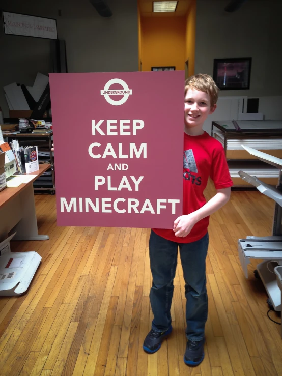 the boy is holding a sign that says keep calm and play minecraft