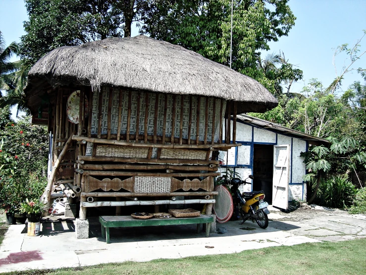 a small house with a thatch roof and a bike in front