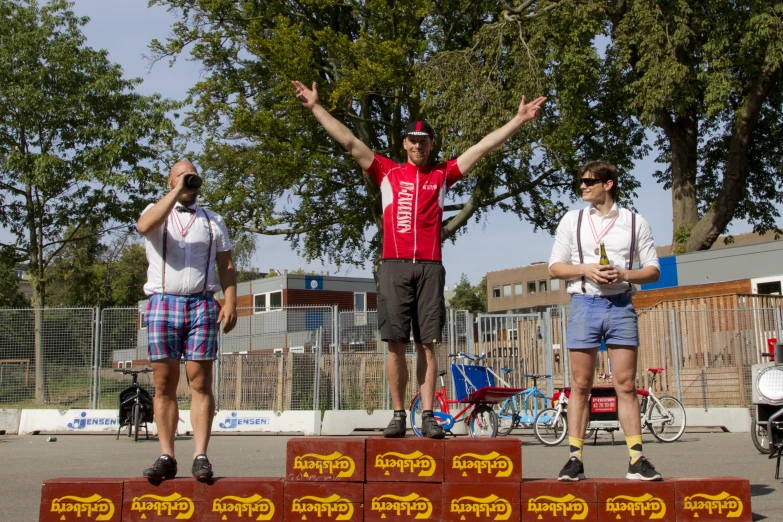 people standing on a street while one man is standing on a podium with his arms in the air