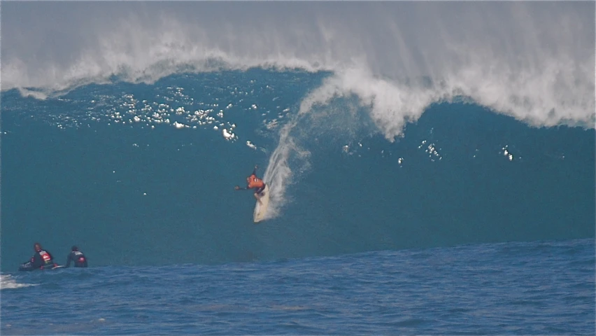 a couple people are riding the huge waves