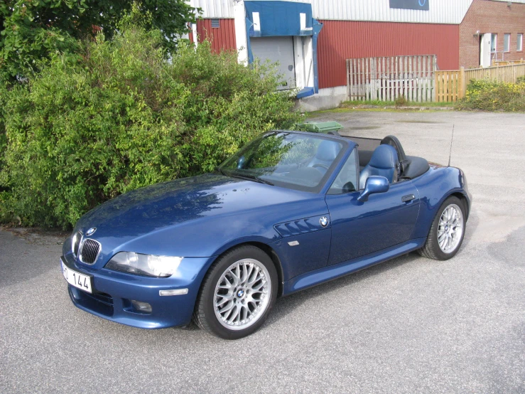 the blue convertible is parked on the side of the road