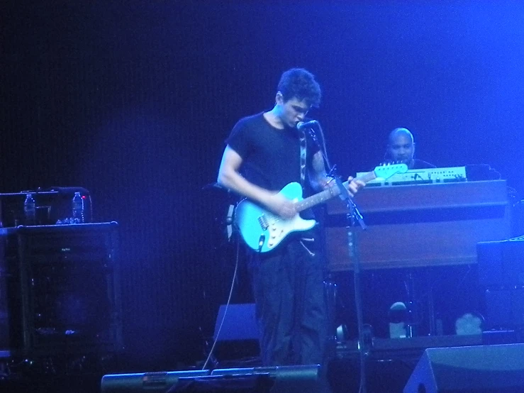 a young man is playing a guitar in front of a keyboard