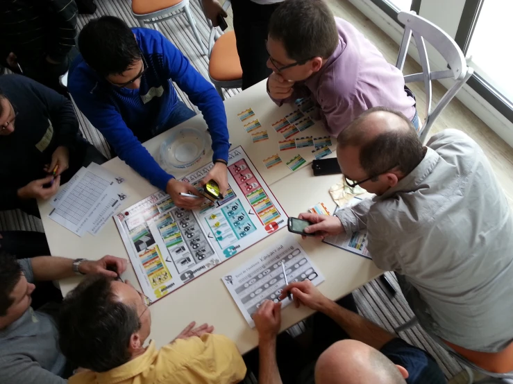 people at table with multiple game and two men holding phones