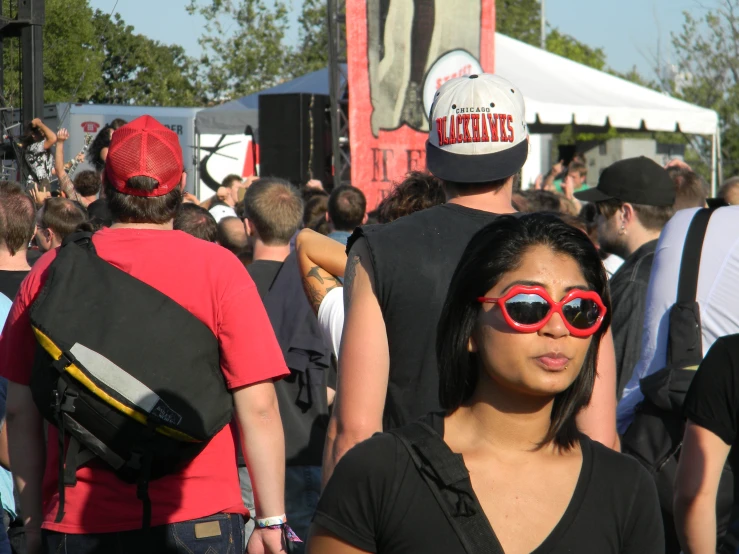 woman in sunglasses and a red hat standing in front of a crowd