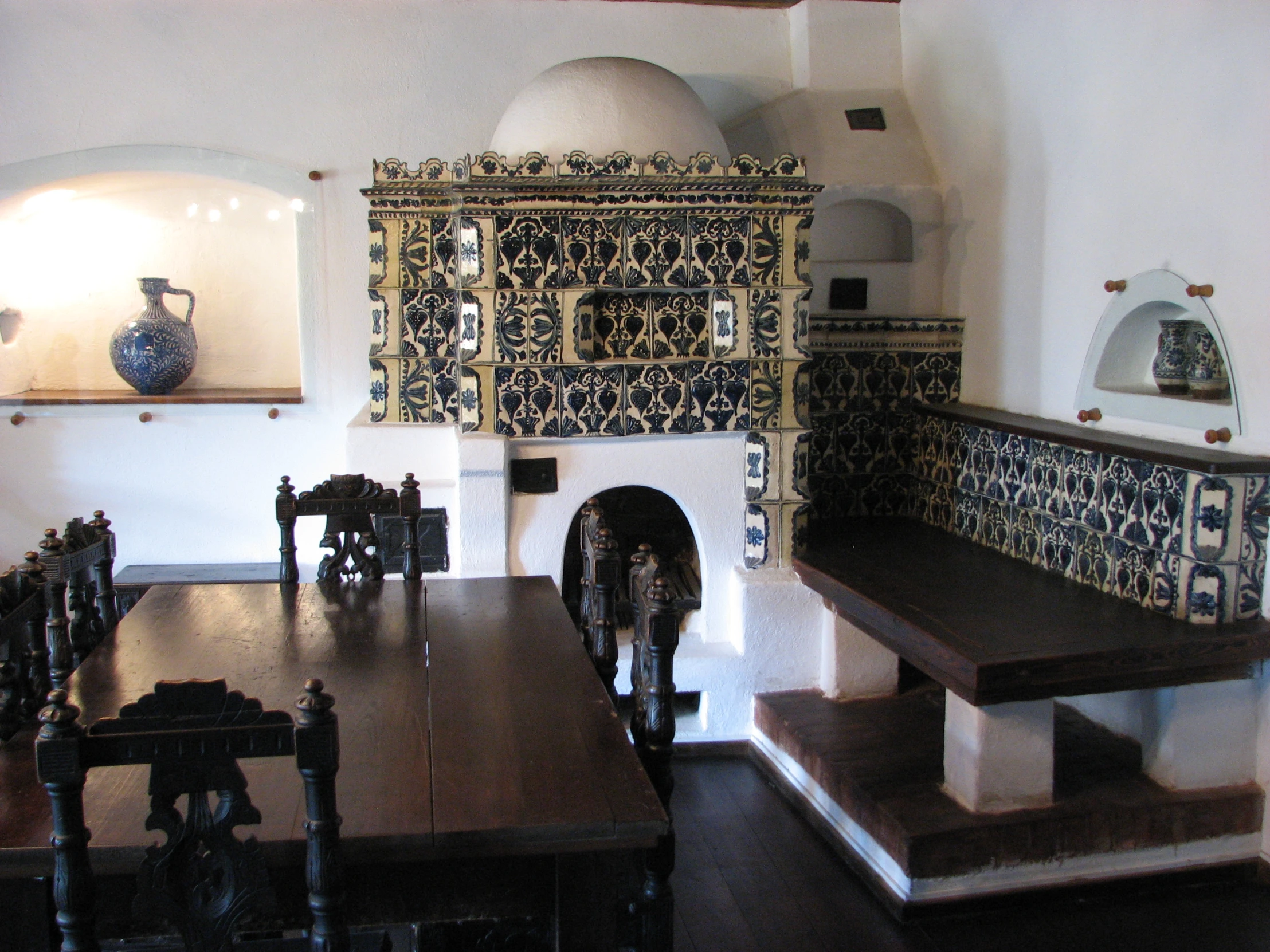 the wooden dining table is sitting in a room with blue and white tiles on the wall