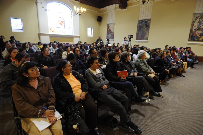 a crowd of people in a room watching some on their laptops