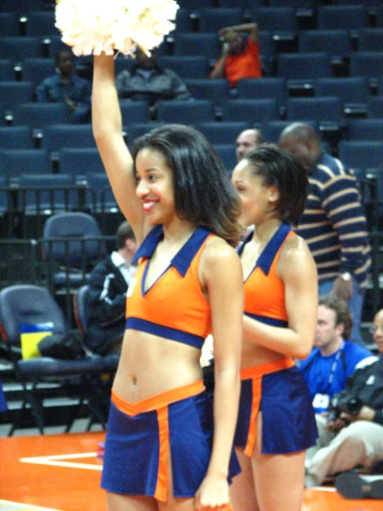 two cheerleaders are in orange and blue outfits holding poms