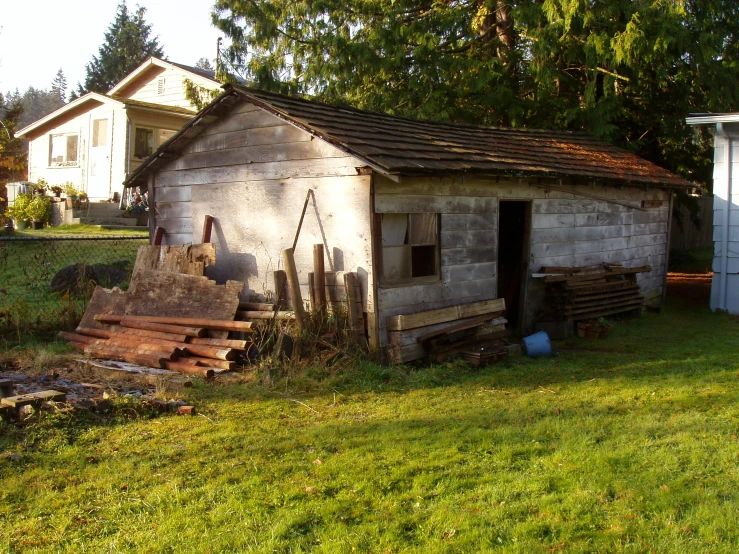 a dilapidated shed with stacks of wood outside