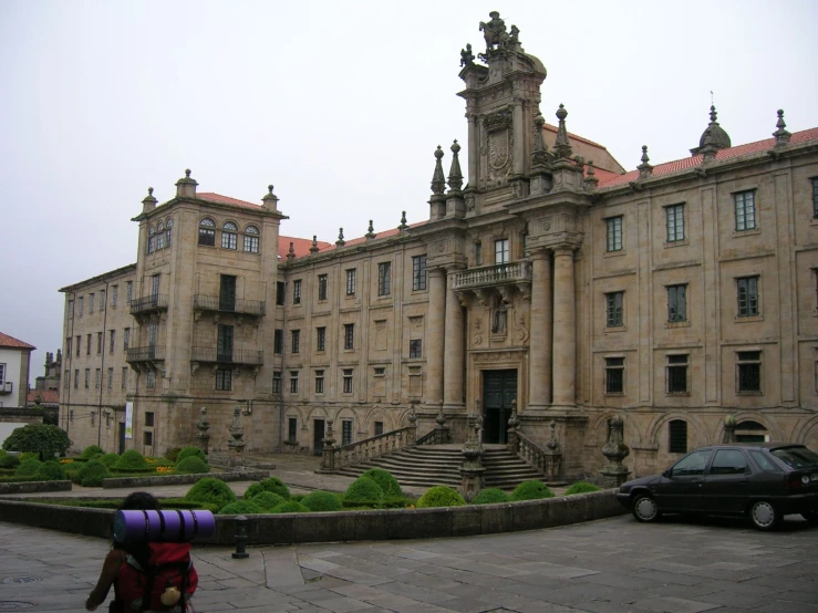 a tall, ornate, stone building with green gardens and bushes