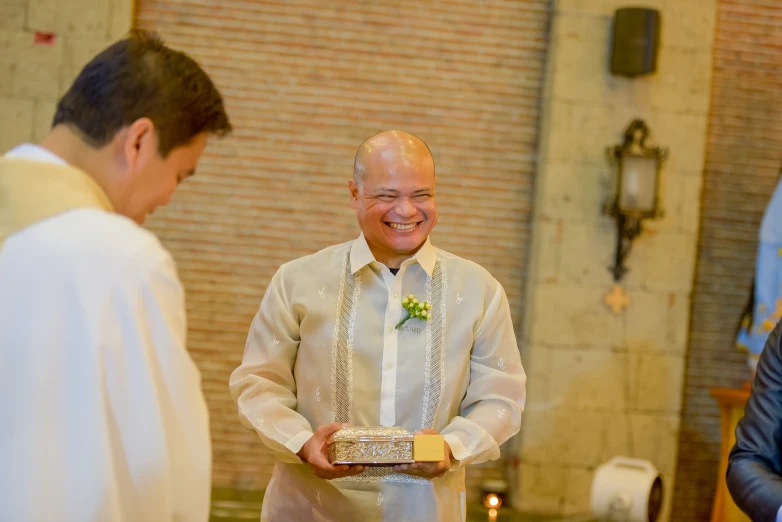 a smiling priest smiles as he holds bread