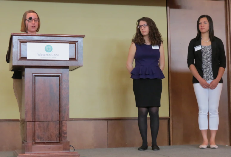 two women are standing at a podium speaking