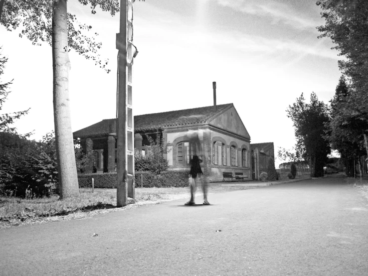 a woman standing on a road by a house