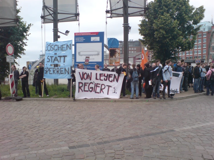 a group of people holding signs near a light post