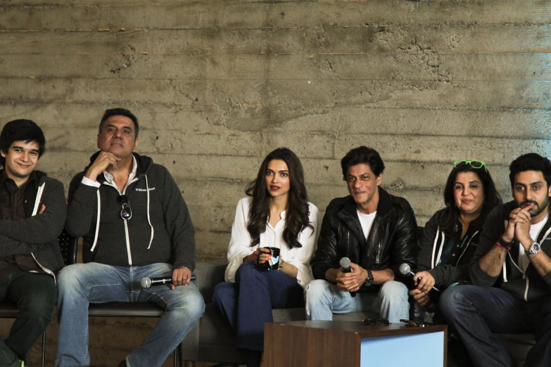 four people sitting in front of a cement wall